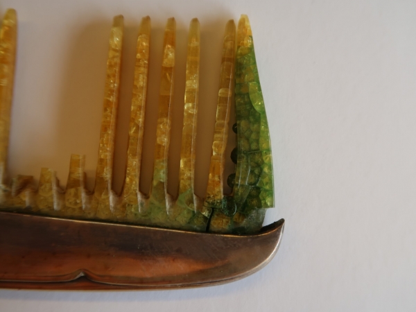 Een kam uit cellulosenitraat in sterk gedegradeerde staat. Het kenmerkende barstenpatroon van cellulosenitraat is hier zichtbaar. Er zijn reeds verschillende tanden van de kam afgebroken. Foto: © Design Museum Gent