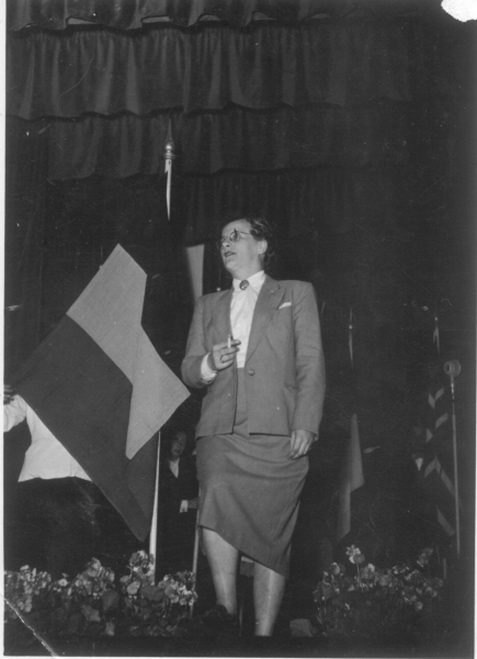 Suzanne De Pues als Suzan Daniel, voor de Belgische vlag op het congres van het International Committee for Sexual Equality, in 1953 in Amsterdam. © Fonds Suzan Daniel