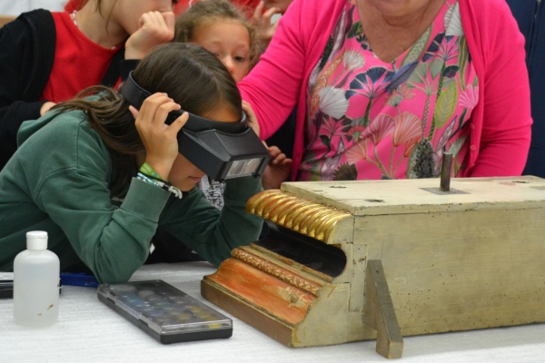 Kinderen kijken door een loepbril in een restauratieatelier © Hof van Busleyden