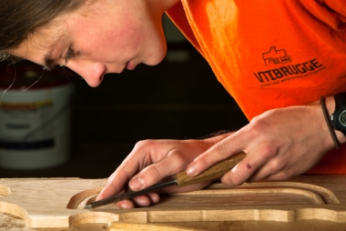 Een leerling van het VTI Brugge kopieert snijwerk van een meubel